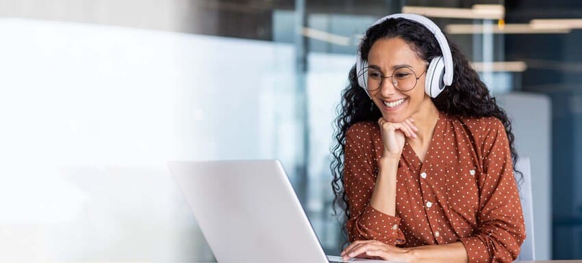 Concentrated man working on a laptop in a well-lit home office with bookshelves