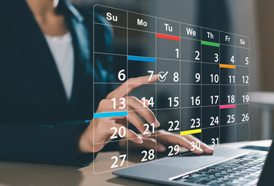 Person using a futuristic digital calendar on a laptop for scheduling tasks.