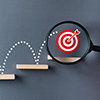 FinAid Thumbnail - Steps leading to a red bullseye target under a magnifying glass, symbolizing strategic goal achievement